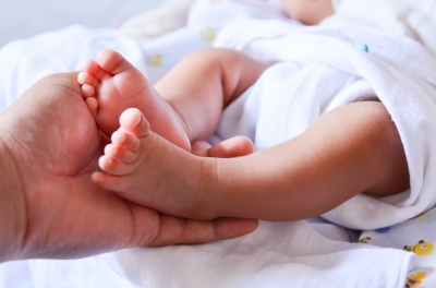Adult hand holding baby's feet