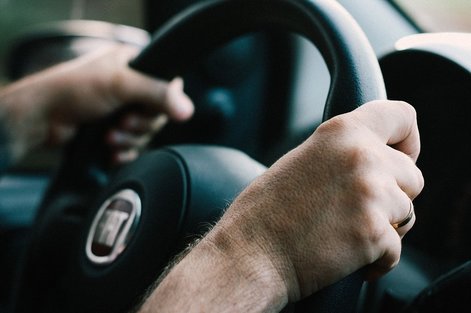 Man holding a car's steering wheel
